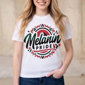 Può includere: T-shirt bianco con la scritta "Melanin Pride" in un design circolare. Il design include accenti neri, verdi e rossi. La maglietta è a maniche corte e ha uno scollo tondo.