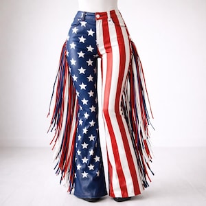 May include: High-waisted, flared pants with a patriotic design. One leg features a blue background with white stars, while the other has red and white stripes. Fringes in red, white, and blue adorn the sides, adding a bold statement.