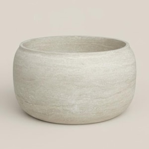 Puede incluir: Un cuenco redondo de piedra gris claro con una superficie texturizada. El cuenco tiene una abertura ancha y una base redondeada. El color neutro y el diseño simple lo hacen adecuado para diversos usos decorativos.