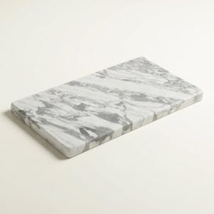 Peut inclure: Une planche à découper rectangulaire en marbre avec un motif veiné blanc et gris. La planche a des coins arrondis et une surface lisse. Cet article de cuisine est idéal pour la préparation et le service des aliments.