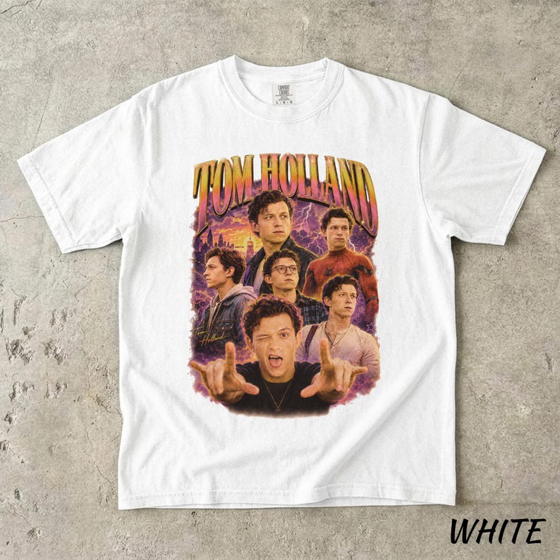 May include: White t-shirt featuring a graphic of Tom Holland in various poses, with the text "TOM HOLLAND" in a retro style. The design includes a purple and orange background.