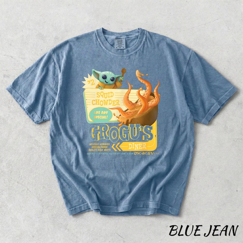 Puede incluir: Camiseta azul vaquero con un gr&aacute;fico de Grogu's Diner, con un personaje de dibujos animados y un cuenco de sopa de calamares. La camiseta tiene el texto "Squid Chowder, Life Day Special!" y "Grogus Diner".