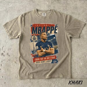 Puede incluir: Camiseta color caqui con un gr&aacute;fico de Kylian Mbapp&eacute;, futbolista, con el texto "MBAPPE" en rojo y azul. La camiseta incluye el n&uacute;mero 10 y las frases "BORN FOR THE BIG STAGE", "SPEED GLORY LEGACY" y el a&ntilde;o 1998.