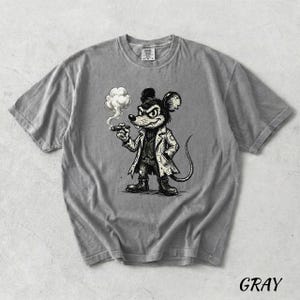 May include: Gray t-shirt featuring a cartoon mouse smoking a cigar. The mouse is dressed in a coat and boots, with a stern expression. The word "GRAY" is printed in the bottom right corner of the shirt.