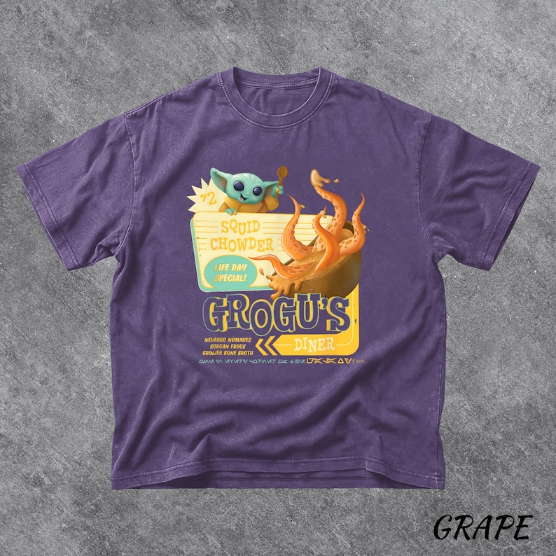 Puede incluir: Camiseta morada con un dise&ntilde;o de Grogu's Diner, con el texto "Squid Chowder" y "Life Day Special!". El dise&ntilde;o incluye una ilustraci&oacute;n de Grogu y un cuenco de comida. La palabra "Grape" est&aacute; en la parte inferior.