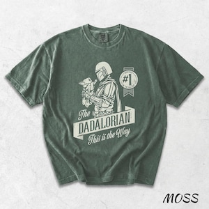 Pu&ograve; includere: T-shirt verde muschio con una grafica di The Mandalorian che tiene Grogu, con la scritta "The DADALORIAN This is the Way". La maglietta ha anche un distintivo "#1 in the Galaxy".