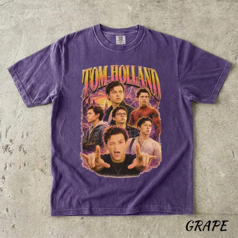 May include: A purple t-shirt featuring a graphic of Tom Holland with the text "TOM HOLLAND" in a retro style. The design includes multiple images of the actor. The word "GRAPE" is printed at the bottom of the shirt.