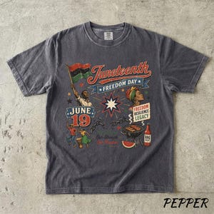 K&ouml;nnte beinhalten: Ein anthrazitfarbenes T-Shirt mit einem Grafikdesign im Vintage-Stil, das den Juneteenth-Feiertag feiert. Das Design enth&auml;lt den Text "Juneteenth Freedom Day", eine Flagge und Illustrationen von Menschen, einem Grill und Wassermelone. Das T-Shirt ist aus weichem, bequemem Material.