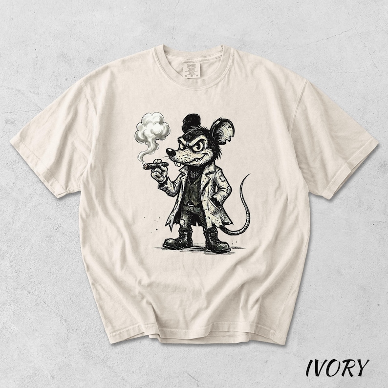 May include: Ivory-colored t-shirt featuring a black and white illustration of a mouse smoking a cigar. The mouse is dressed in a coat and hat, with a stern expression. The word "IVORY" is printed at the bottom of the shirt.