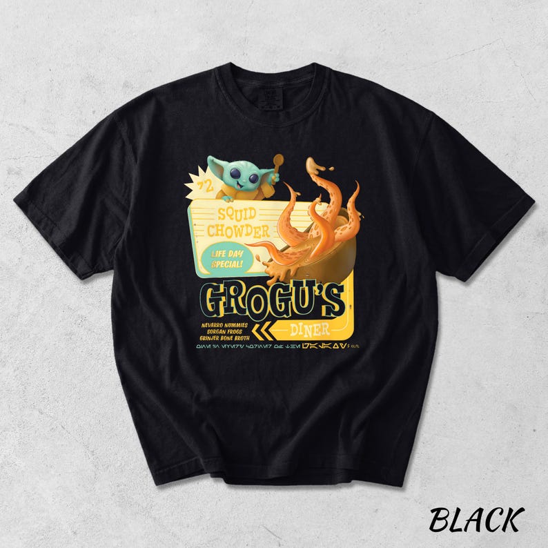 Puede incluir: Camiseta negra con un dise&ntilde;o de dibujos animados de Grogu's Diner. El gr&aacute;fico incluye a Grogu, un cuenco de sopa de calamares y el texto "Squid Chowder, Life Day Special!". La camiseta tambi&eacute;n presenta el texto "Grogu's Diner" en un estilo retro.