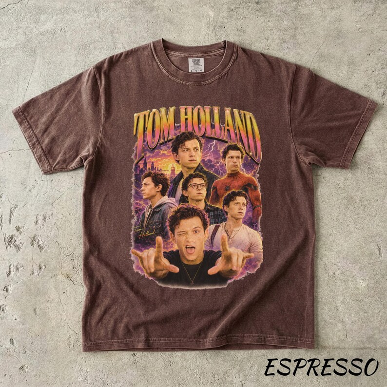 May include: Espresso-colored t-shirt featuring a graphic of Tom Holland in various poses, with the text "TOM HOLLAND" in a retro font. The shirt has a crew neck and short sleeves, and the word "ESPRESSO" is printed at the bottom.