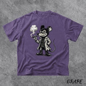 May include: A purple t-shirt featuring a cartoon mouse in a white coat, smoking a cigar. The mouse has a stern expression. The word "GRAPE" is printed in the bottom right corner of the shirt.