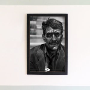 Puede incluir: Fotografía en blanco y negro de un hombre con bigote, vistiendo una chaqueta de traje, enmarcada en un marco negro.