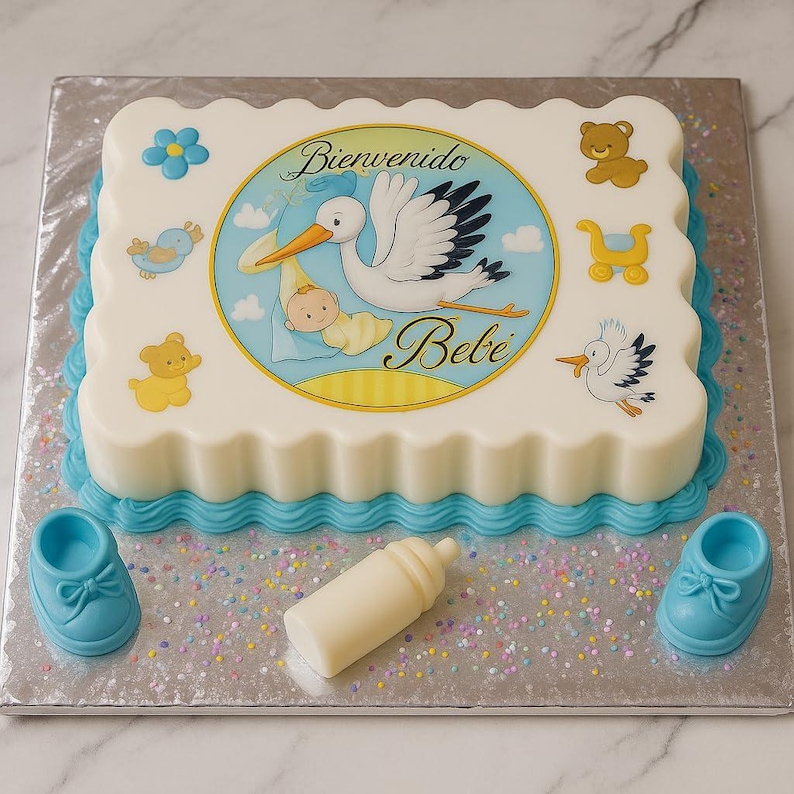 Puede incluir: Una tarta de baby shower con un dise&ntilde;o blanco y azul. La tarta presenta una cig&uuml;e&ntilde;a que lleva un beb&eacute;, con las palabras "Bienvenido Bebe". Decoraciones adicionales incluyen un biber&oacute;n y zapatos de beb&eacute; azules.
