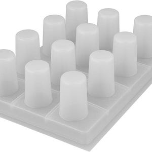 May include: A white plastic tray with twelve cylindrical, rounded-top pegs arranged in a grid pattern. The pegs are evenly spaced and appear to be made of a translucent material. The tray has a textured surface.