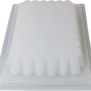 May include: A clear, rectangular mold with a scalloped edge, nested inside a larger, rectangular tray. The mold and tray are made of a translucent, white material. The design is simple and functional, suitable for baking or crafting.