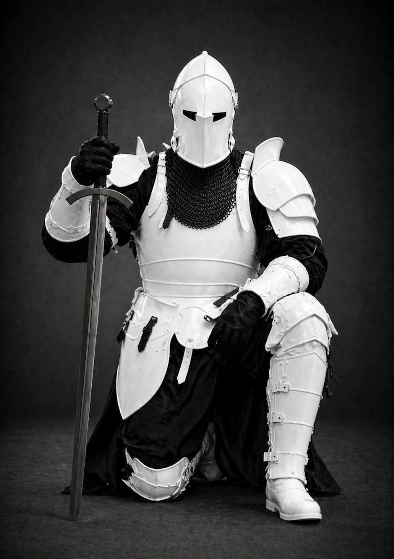 May include: A black and white image of a knight kneeling, holding a sword. The knight is clad in white armor, including a helmet, shoulder guards, and leg protection. A chainmail collar and black gloves are also visible. The sword is long and silver.