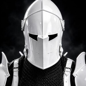 May include: A white knight's helmet with a visor and a black background. The helmet is part of a suit of armor, with shoulder guards and a chainmail collar. The helmet has a smooth, reflective surface.