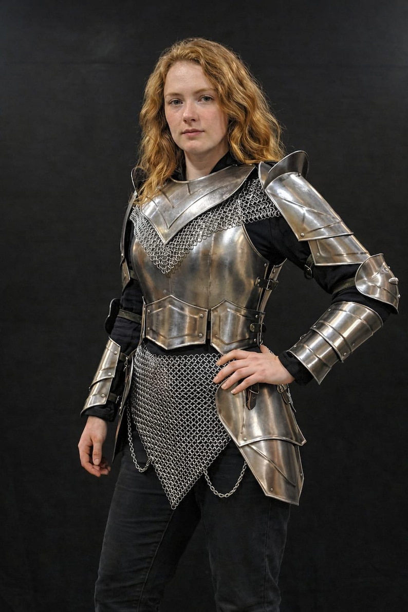 May include: A polished steel plate armor set featuring a breastplate, pauldrons, and articulated arm guards. The armor includes integrated chainmail sections at the neck and waist, with leather straps and buckles securing the metal components.