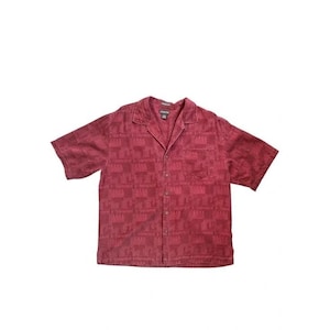 May include: A short-sleeved, button-down shirt in a deep burgundy color. The shirt features a subtle, repeating pattern and a classic collar. It has a single chest pocket and is made of a textured fabric.