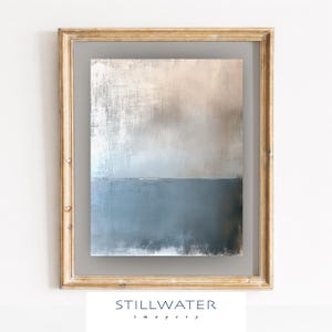 May include: Abstract painting in a gold frame. The artwork features a textured, layered design with a gradient of colors, transitioning from a light beige at the top to a deep blue at the bottom. The frame is a light gold color. The text "STILLWATER imagery" is at the bottom.