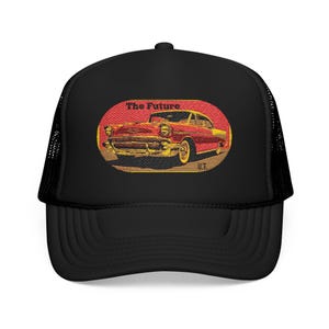 Puede incluir: Gorra de camionero negra con un diseño gráfico rojo y amarillo de un coche clásico. El gráfico está dentro de un óvalo y tiene las palabras "The Future" encima del coche. La gorra tiene una parte trasera de malla negra y una visera curva.