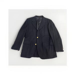 May include: A navy blue blazer with two front pockets and gold-colored buttons. The jacket has a classic design with a notched lapel and a tailored fit. The blazer is made of a textured fabric.