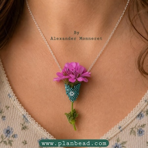 Könnte beinhalten: Halskette mit Anhänger, der eine rosa Blume in einem türkisblauen Perltopf zeigt. Die Kette wird getragen. Der Text "By Alexander Monneret" befindet sich über dem Anhänger. Die Website "www.planbead.com" befindet sich unten.