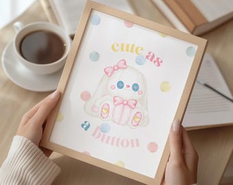 May include: A framed print with a cartoon bunny illustration, complete with a pink bow and gift. The text "cute as a button" is displayed on the print, which is decorated with pastel polka dots. The frame is light wood.
