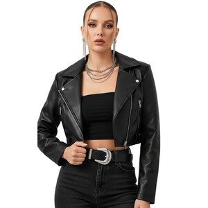May include: A black faux leather motorcycle jacket with a notched collar, asymmetrical zipper closure, and silver hardware. The jacket features a cropped length and is paired with a black belt with a silver buckle. The model is wearing a black tube top and black jeans.