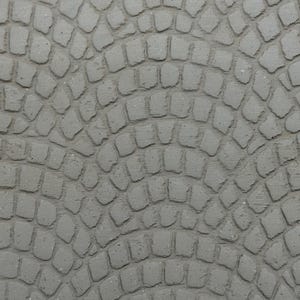 May include: Close-up of a gray, textured surface with a pattern of cobblestones arranged in a semi-circular design. The stones are irregular in shape and have visible grout lines.