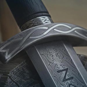 May include: Close-up of a detailed sword with a patterned blade and handle. The metalwork features intricate designs and a dark, textured handle. The sword's guard has a decorative, curved shape.
