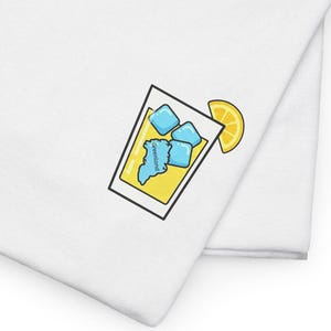 May include: Two white t-shirts are stacked, with a cartoon graphic of a cocktail glass on the front. The glass is yellow with blue ice cubes and a lemon slice. The design is outlined in black.