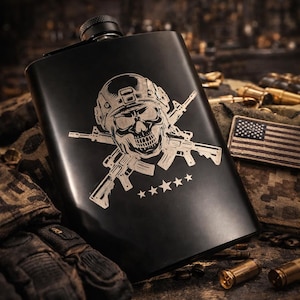 May include: Black laser-engraved flask with a skull wearing a helmet and crossed rifles design. The flask has the text "LASER-ENGRAVED FLASK", "Hardcore Gifts • Gifts for Veterans", and "BUILT FOR THE TOUGH".