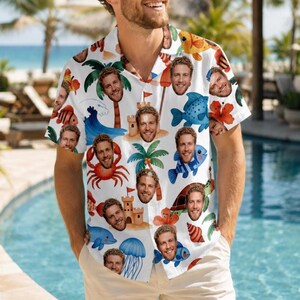 May include: White short-sleeve button-down shirt with a tropical pattern featuring cartoon fish, palm trees, sandcastles, and a smiling face. The shirt is a fun, colorful design, perfect for a summer vacation or beach day.