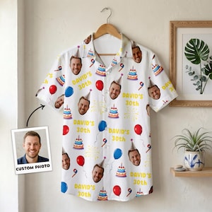 May include: White button-down shirt featuring a repeating pattern of a man's face, birthday cakes, balloons, and the text "DAVID'S 30th". The shirt is displayed on a wooden hanger. A photo with the text "CUSTOM PHOTO" is in the lower left corner.