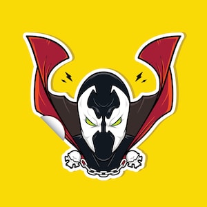May include: A sticker featuring a cartoon illustration of a character with a white mask, black head and cape, and green eyes. The character has a red cape and is on a yellow background. Two lightning bolts are above the character's head.