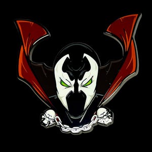 Pode incluir: Pin do personagem Spawn em um fundo preto. O pin apresenta o rosto branco do personagem com olhos verdes, um capuz preto e uma capa vermelha. Duas caveiras ladeiam uma corrente prateada.