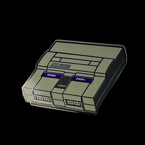 May include: A pin shaped like a Super Nintendo console. The pin is gray with purple buttons labeled "POWER" and "RESET", and a black button labeled "EJECT". The words "SUPER NINTENDO" are printed on the top of the console.