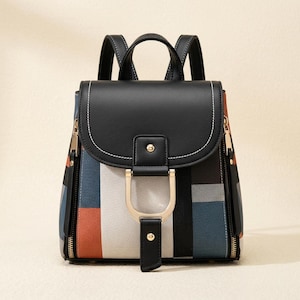 May include: A stylish backpack with a black top flap and handles. The body features a colorful geometric pattern in blue, red, and white. Gold-toned hardware accents the front, and zippers run along the sides.