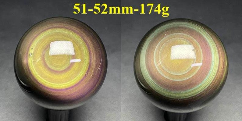 May include: Two polished obsidian spheres, each with a swirling pattern of yellow, purple, and green. The spheres are approximately 51-52mm in diameter and weigh 174g. The text "51-52mm-174g" is displayed above the spheres.