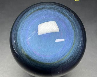May include: A polished, spherical gemstone with a swirling blue and black pattern. The sphere measures approximately 1.65 to 2.05 inches in diameter and weighs 6.45 ounces. The text "42-52mm-183g" is visible at the top.