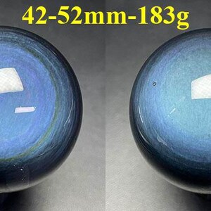 May include: Two polished blue obsidian spheres. The spheres have a reflective surface with a swirling pattern of blue and black. The text "42-52mm-183g" is in the top center.