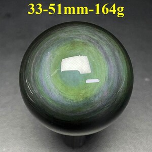 May include: A polished, spherical obsidian stone with a swirling pattern of green, gray, and black. The text "33-51mm-164g" is visible at the top. The stone measures approximately 1.3 to 2 inches in diameter and weighs about 5.8 ounces.