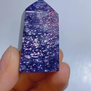Pu&ograve; includere: Una punta di cristallo lucidata a forma di torre con una base color viola intenso e macchie metalliche iridescenti incastonate che brillano in tonalit&agrave; rosa, blu e argento su tutta la superficie della pietra, creando un aspetto galattico.