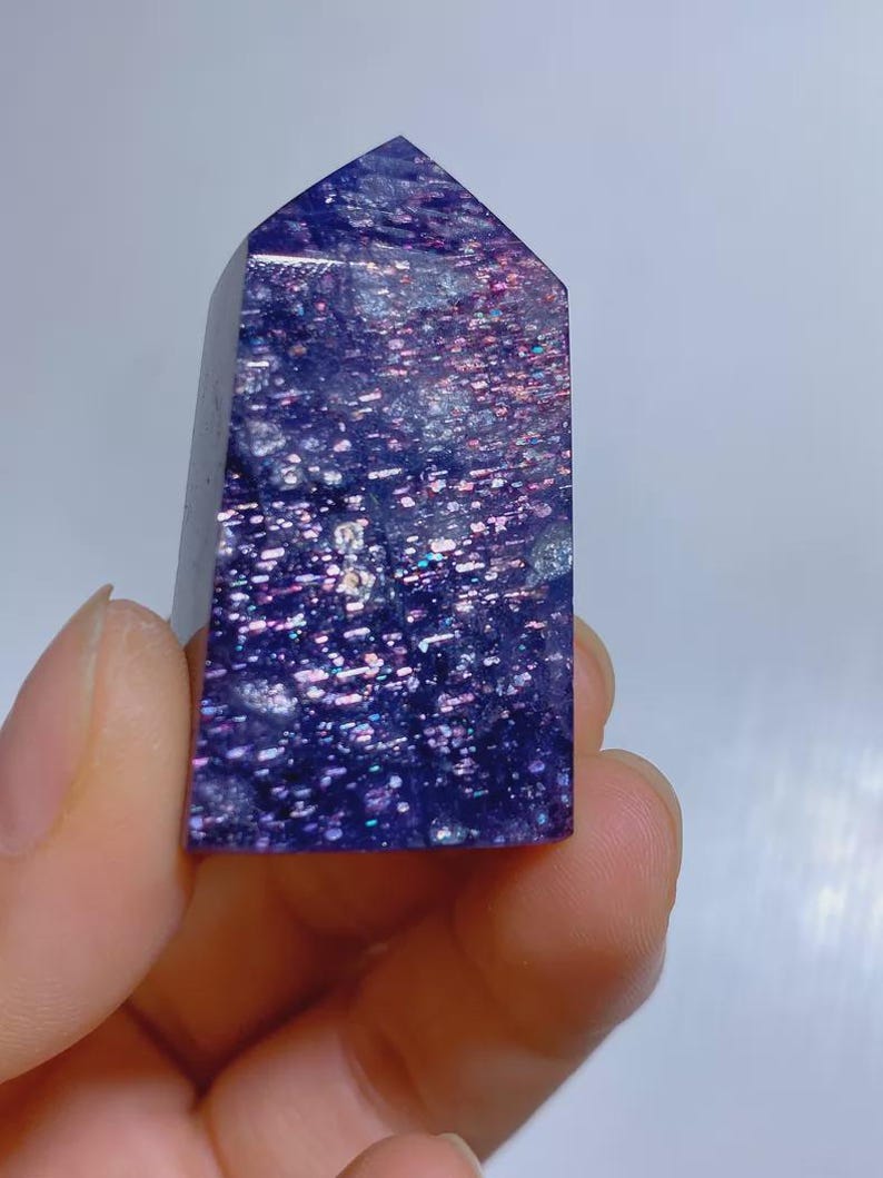 Pu&ograve; includere: Una punta di cristallo lucidata a forma di torre con una base color viola intenso e macchie metalliche iridescenti incastonate che brillano in tonalit&agrave; rosa, blu e argento su tutta la superficie della pietra, creando un aspetto galattico.