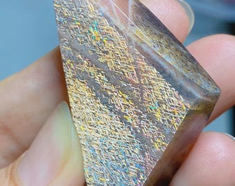 Op de afbeelding: Een gepolijste zonnesteen kristalpunt met een driehoekige vorm en een glad oppervlak. De steen heeft een warme bruine basiskleur met een ingewikkeld, kruislings patroon van glinsterende, iriserende metalen insluitingen die het licht reflecteren.