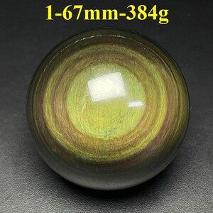 May include: A polished, spherical gemstone with a swirling pattern of olive green and brown hues. The text "1-67mm-384g" is visible at the top. The sphere measures approximately 2.6 inches in diameter and weighs about 13.5 ounces.