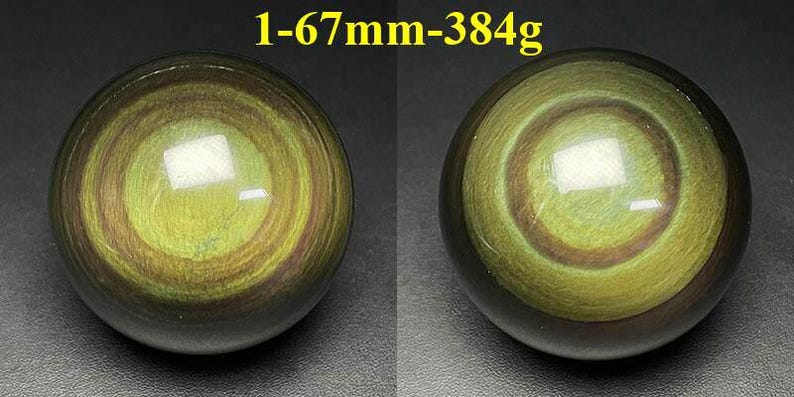 May include: Two polished obsidian spheres, each with concentric rings of olive green and brown hues. The spheres are approximately 2.6 inches in diameter and weigh 13.5 ounces. The text "1-67mm-384g" is visible above the spheres.