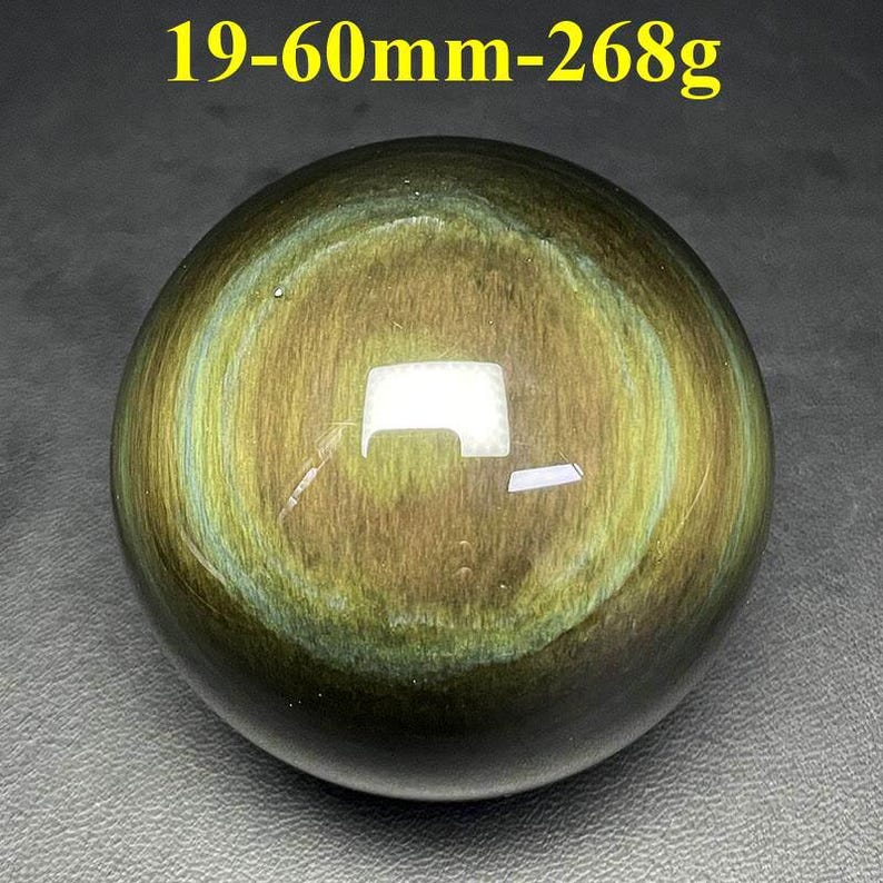 May include: A polished, spherical gemstone with a swirling pattern of gold and green hues. The text "19-60mm-268g" is visible at the top. The sphere is approximately 2.36 inches in diameter and weighs 9.45 ounces.